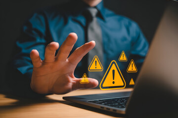 Businessman blocking warning signs on laptop, representing cybersecurity threat and data protection