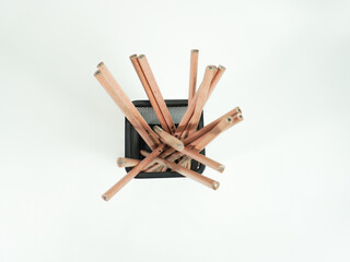 Pencils in a black wire basket, symbolizing creativity, writing, and design on a white surface