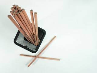 Wooden pencils in black mesh holder on a white surface, perfect for creative projects