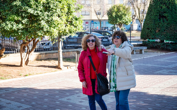 Two senior women walking together and talking on a sunny day in the city