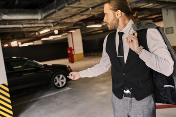 A handsome bearded man in a sleek suit stands near his car in a stylish underground garage.