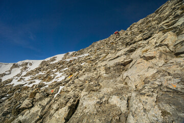 View of a rugged, rocky mountain slope with patches of snow under a clear blue sky, a challenging climb, Litochoro, Larisa, Greece.