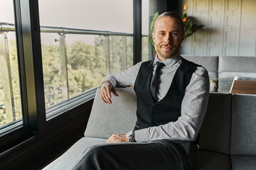 Handsome businessman in elegant attire relaxes at a modern cafe, exuding confidence and wealth.