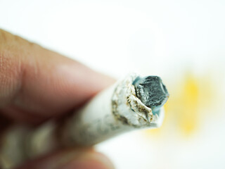 Close-up of a finger holding a used cigarette butt with a burnt filter against a blurred background