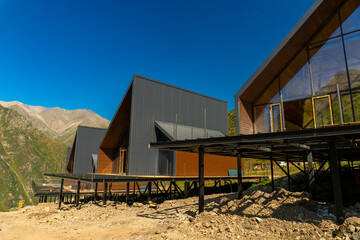 Cluster of Scandinavian, mountain A-frame chalets built on steel stilts, angular roofs, large glass...