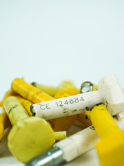 Pile of yellow and white industrial components, some marked with numbers and symbols, showing wear and tear.