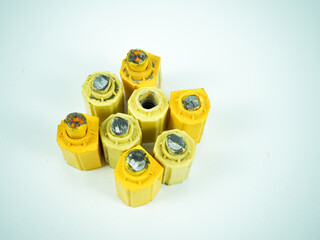 Group of weathered yellow hexagonal industrial components with metal inserts on a clean white...