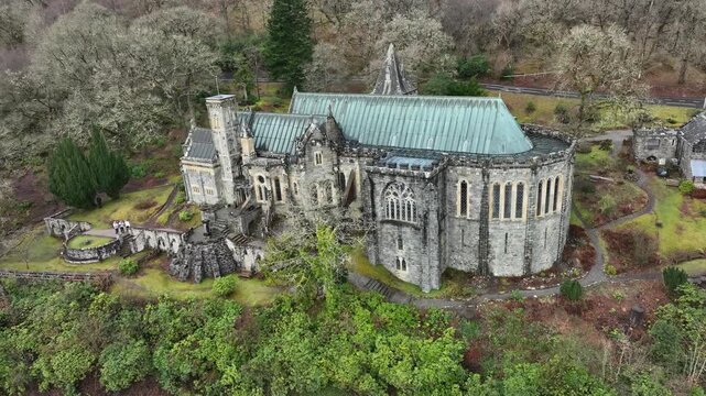 Aerial view of St Conan's Kirk, a beautiful historic church with a green roof, nestled among lush trees and gardens, Dalmally, United Kingdom.