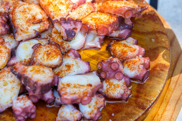 Galician-style Octopus Pulpo a Feira with Smoked Paprika and Sea Salt on a Wooden Plate. Concept: Spanish cuisine