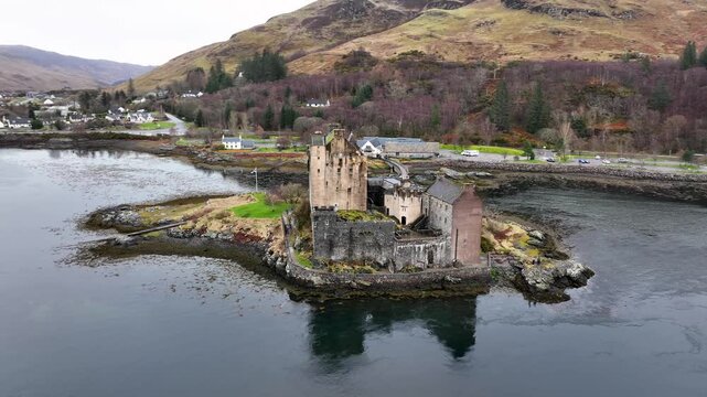 Aerial view of the historic Eilean Donan Castle standing proudly on a small island, its stone walls reflecting in the surrounding water, Kyle of Lochalsh, United Kingdom.