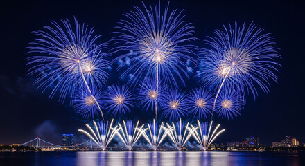 Spectacular blue fireworks lighting up the night sky over city skyline and river during celebration festival event
