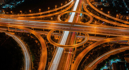 Aerial View of Night Highway Interchange with Light Trails and Urban Roads