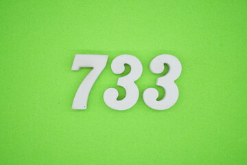 The numbers are made of white painted wood and placed on a green paper background.