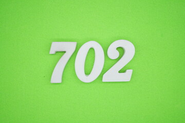 The numbers are made of white painted wood and placed on a green paper background.