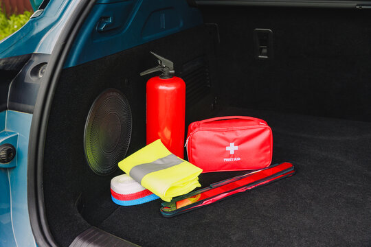 The interior of the trunk of the car in which there is a first aid kit, fire extinguisher, warning triangle, reflective vest and tow rope.