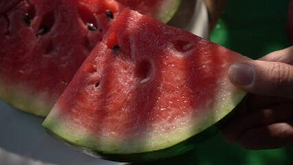Hand picking up slice of watermelon from plate