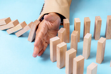 A Hand Stops Falling Dominoes Mid-Sequence, Symbolizing Interruption And Control In Business