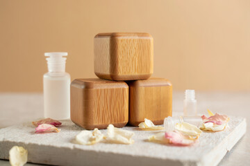 Natural wooden cubes with rose petals and essential oil bottle, spa and wellness concept