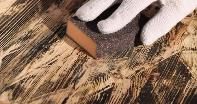 hard sandpaper on sponge for manual polishing of wooden surfaces, wooden board made of pine planks for polishing with sandpaper on the construction site