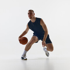 Man dribbling basketball on white background in athletic motion. Concept of preparation, tactical...