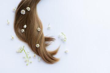 Female hair with white merry bells flowers. Closeup, on a white background.