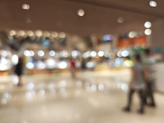 Abstract bokeh image of a bustling shopping mall with blurred lights and figures.