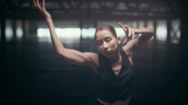 Zoom in shot of young Caucasian woman dancing experimental solo in warehouse