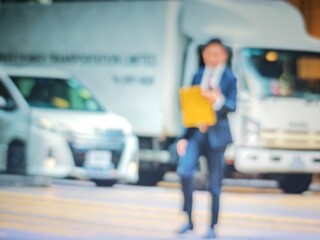 Abstract bokeh image of a person holding a yellow object near a white van on a city street.
