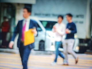 Abstract bokeh image of people walking on city street, blurred background.