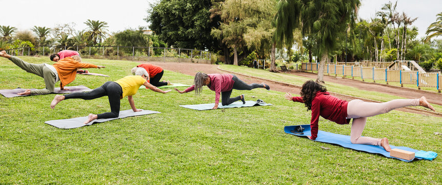 Group of people doing yoga class at city park - Multiracial women doing zen meditation outdoor - Healthy and spiritual lifestyle concept - Main focus on right people bodies