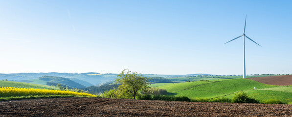countryside landscape in luxemburg with wind turbine under blue sky in spring