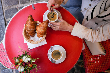 Breakfast scene with coffee and croissants on red cafe table viewed from above