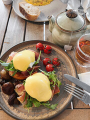 Eggs Benedict with Bacon, Mushrooms, Greens and Tomatoes. Savoury breakfast meal