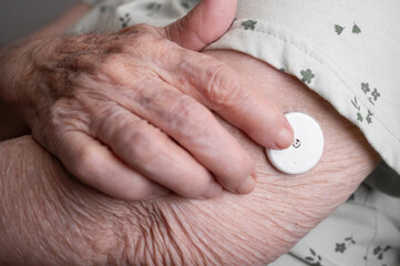 Elderly patient applying glucose sensor on arm for diabetes control