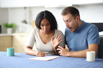 Amazed interracial roommates reading contract in a kitchen