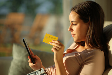 Serious woman buying online with a warm light at home