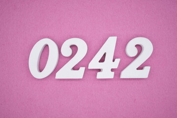 The numbers are made of white painted wood, placed on a pink paper background.