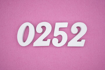 The numbers are made of white painted wood, placed on a pink paper background.