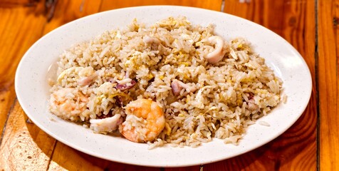 A plate of seafood fried rice, a popular dish found in various cuisines worldwide.Its contains shrimp and  cuttlefish, along with scrambled egg and rice. 