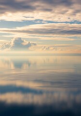 Obraz premium Serene Sky and Sea Reflection - Peaceful of clouds reflected on calm water, creating a beautiful mirrored effect. Soft pastel colors dominate the scene