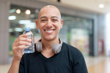 Man drinking water in mall food court, hydration and wellness focus