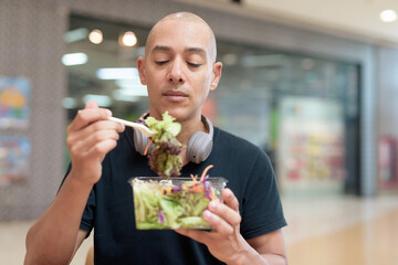 Man eating healthy salad in food court, health and wellness lifestyle