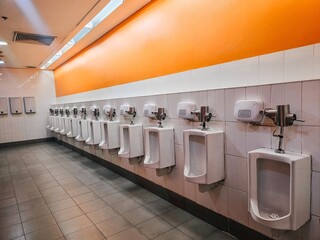 This is a men's public restroom equipped with clean urinals and well-lit surroundings, ensuring a hygienic and comfortable environment for users.