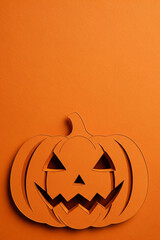 A Paper Cutout Jack-O'-Lantern with a Spooky Face and Shadows on a Solid Orange Background, with Ample Vertical Copy Space for Halloween Designs