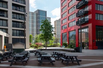Modern urban courtyard with picnic tables and buildings.