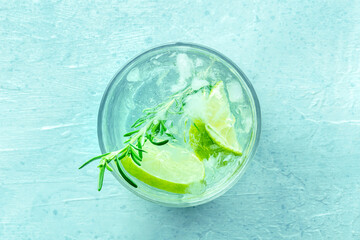 Gin tonic, overhead flat lay shot with rosemary and lime. Fresh summer drink with ice