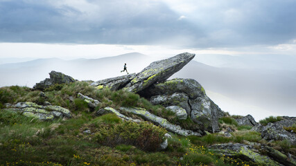 Personal challenge, achievement, goal. Collage of runner leaping over large rocky ledge with misty mountains in background. Concept of fitness challenge, mental resilience.