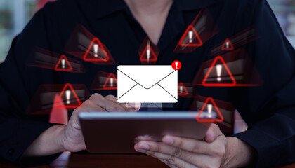 Email phishing attack warning, digital alert signs surrounding a person using a tablet, representing online scam threats and cybersecurity risks in electronic communication.