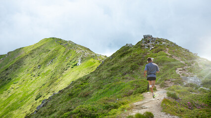 Bold handmade collage of male runner climbing rocky trail on mountain ridge under dramatic sky....