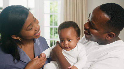 Smiling Parents Holding Their Baby at Home, Sharing a Loving Family Moment